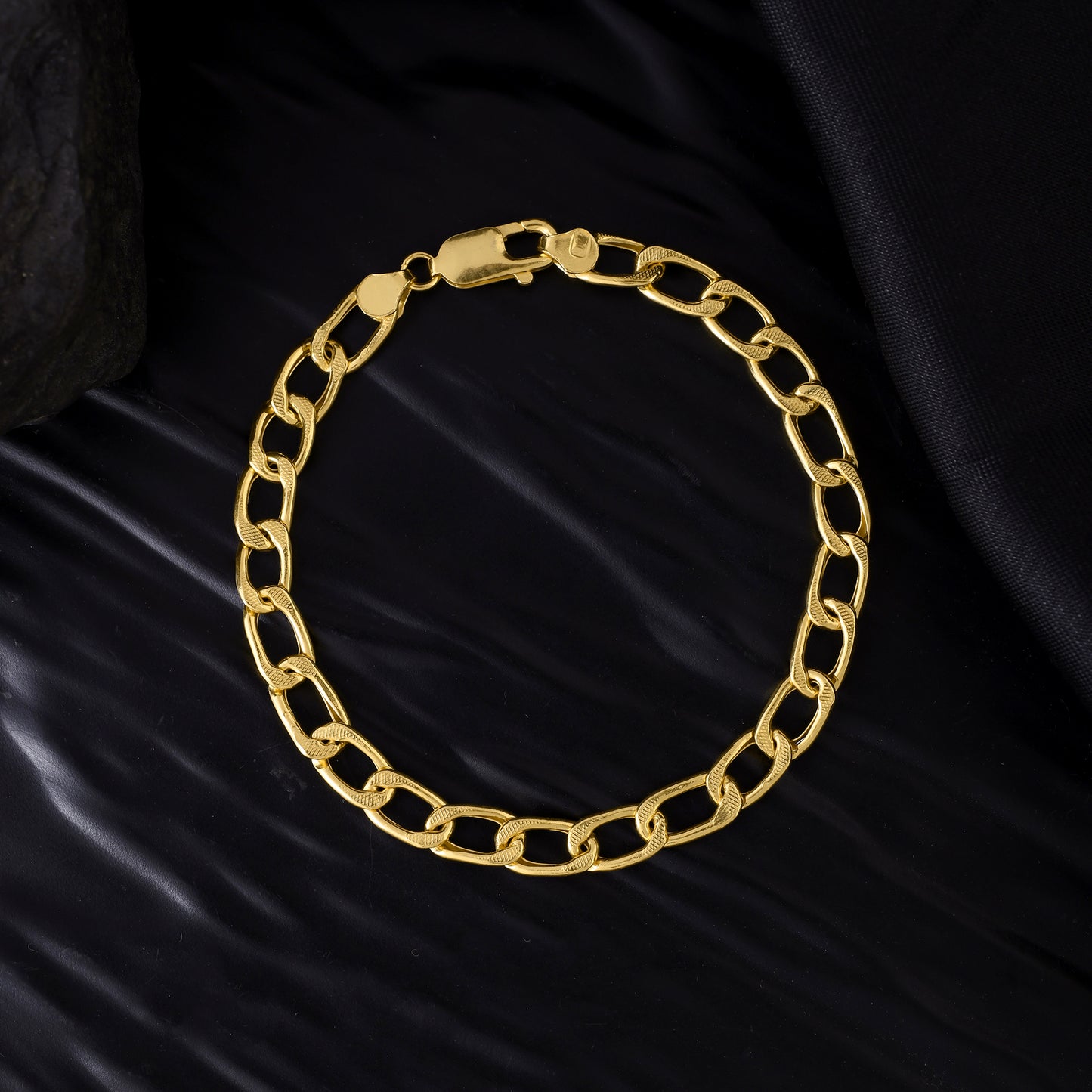 Close-up view of a gold chain bracelet for men. The elegant piece of jewelry features a polished finish and a timeless design.