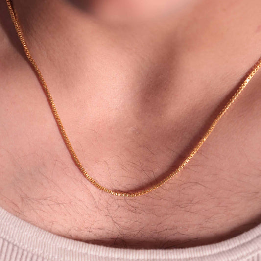 Textured gold box chain necklace displayed on a men's chest, The classic design makes it a timeless piece of gold jewellery for male.