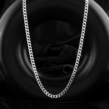 A 925 sterling silver thick cuban chain takes center stage in this close-up. Its polished links create a geometric pattern with a hint of shine