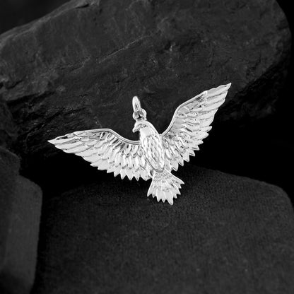 A detailed bird pendant for men in sterling silver captures the essence of flight, its wings reaching outward. 