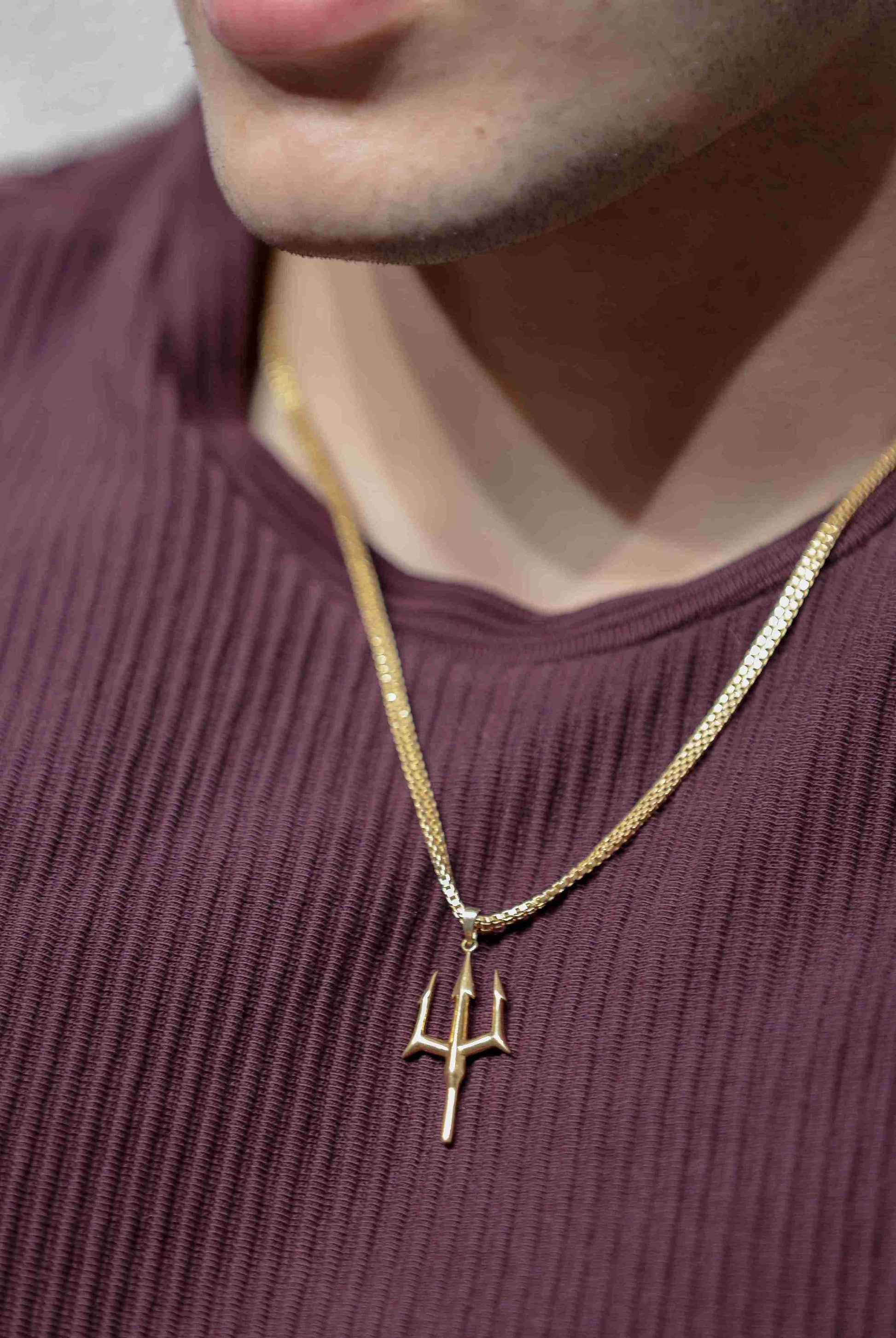 A gold trident  men necklace. The pendant is in the shape of a three-pronged trident and hangs from a latest gold chain design.