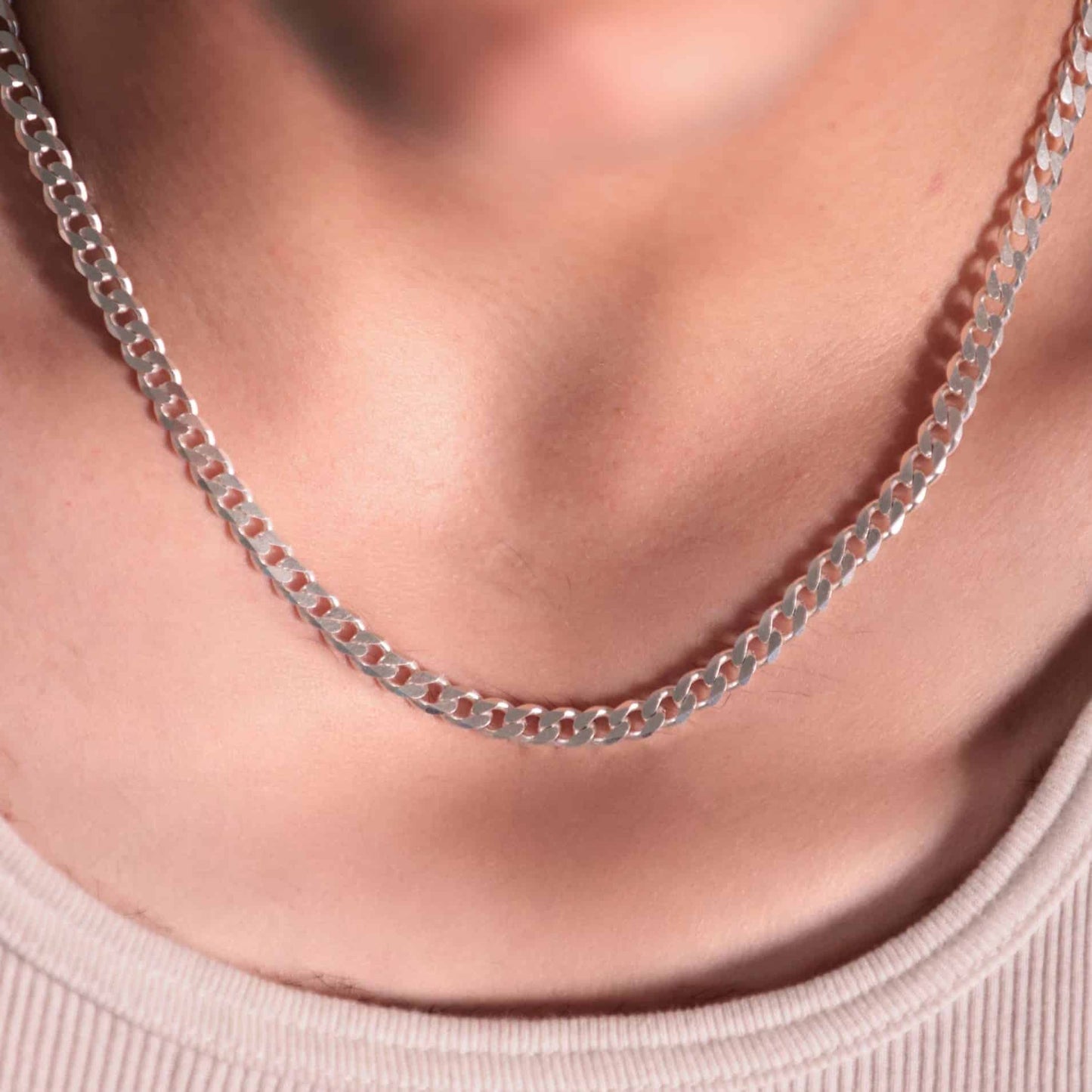 Pure silver thick cuban chain showcased in detail. The flat, interlocking links create a classic design with a hint of edge, captured close-up.