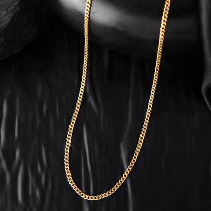 A thin gold cuban chain necklace, captured close-up. The polished curb links shimmer with a classic elegance perfect for boys chain design