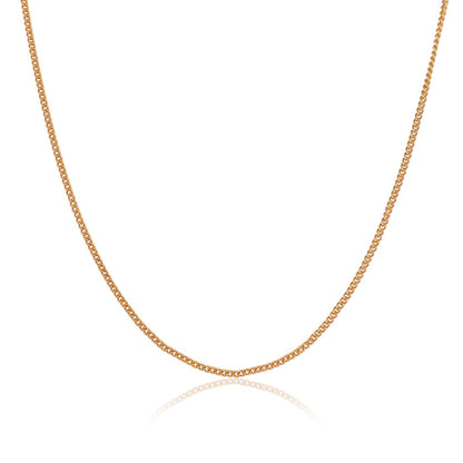 Close-up of a gold link neck chain for men. The shiny links cast a soft reflection on a white surface.