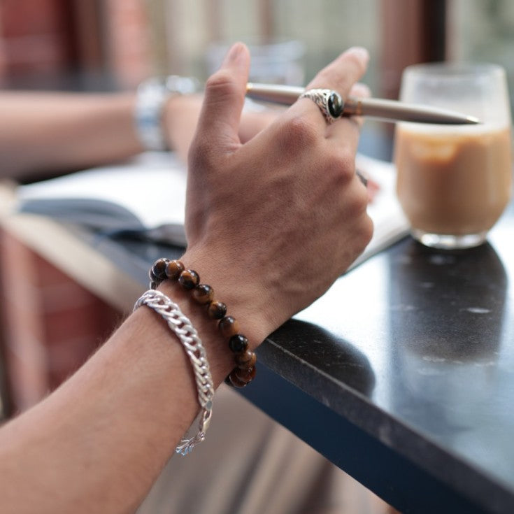 Stackable bracelet made with tiger's eye beads. The polished stones, photographed up close, display a beautiful mix of brown, gold, and black with a shimmering luster.