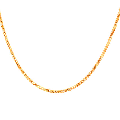 Close-up of a gold plated silver link chain for men. The shiny links cast a soft reflection on a white surface.