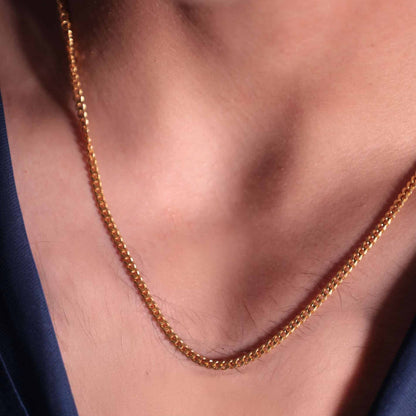 Close-up of a man's neck with a gold chain. The intricate design of the chain catches the light, creating a sense of texture and style.